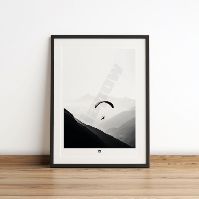 Photo noir et blanc d’un parapente dans les airs au-dessus des montagnes. Affiche murale design pour décoration moderne.