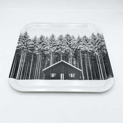 Küchenbrett aus Holz von Diapow mit der Abbildung einer Hütte vor einem Wald aus schneebedeckten Tannen in Schwarz-Weiß.