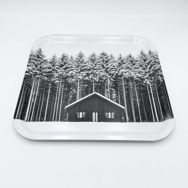 Küchenbrett aus Holz von Diapow mit der Abbildung einer Hütte vor einem Wald aus schneebedeckten Tannen in Schwarz-Weiß.