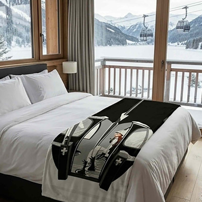 XL white throw blanket, soft and thick, featuring a black cable car illustration and a female skier, placed on a bed.